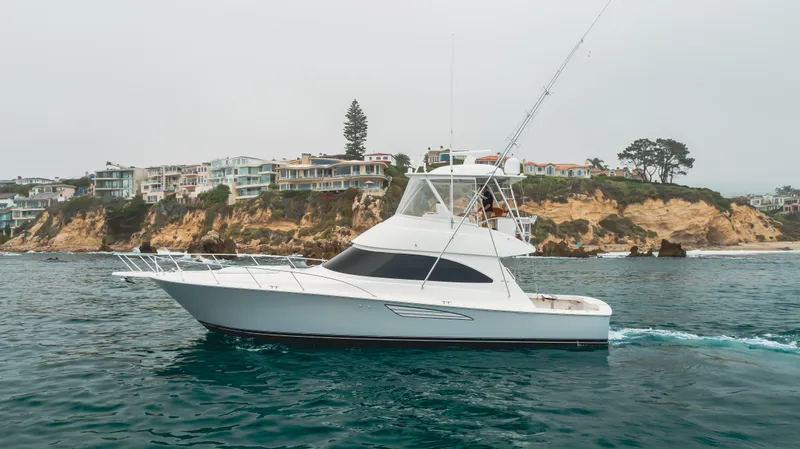 Slide: The Image of 2017 Viking 48 Convertible yacht cruising near scenic coastal cliffs. - 3