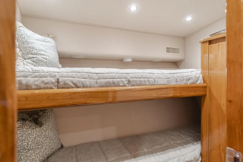 Slide: The Image of Bunk beds in 2017 Viking 48 Convertible yacht cabin, featuring cozy bedding and wooden accents. - 36