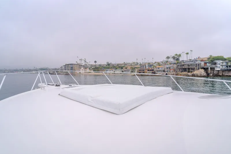 Slide: The Image of Viking 48 Convertible yacht, 2017 model, cruising near coastal homes under cloudy skies. - 7