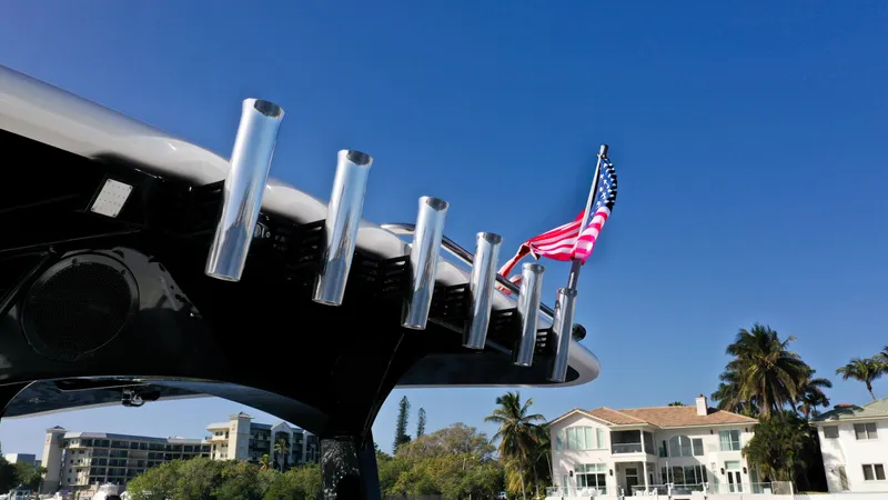 Slide: The Image of 2022 HCB 42 Lujo boat with American flag, rod holders, and waterfront homes in the background. - 18