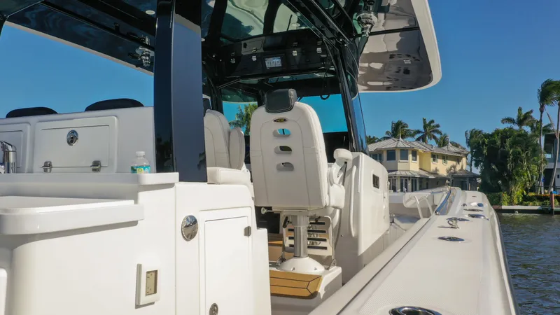 Slide: The Image of 2022 HCB 42 Lujo boat interior with helm seats and console, docked by waterfront homes. - 24