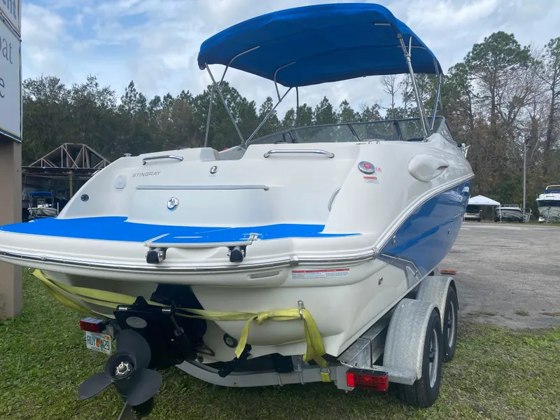 Slide: The Image of 2019 Stingray 250CR boat with blue canopy on trailer, parked outdoors. - 3