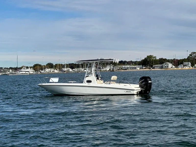 Slide: The Image of 2019 Boston Whaler 240 Dauntless boat on calm water near marina. - 2
