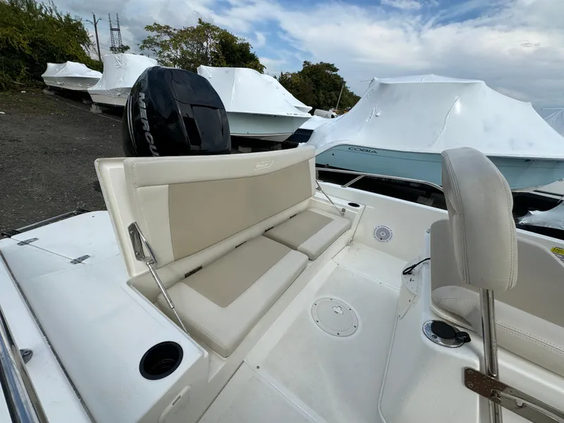 Slide: The Image of 2019 Boston Whaler 240 Dauntless boat interior with cushioned seating and covered boats in background. - 4