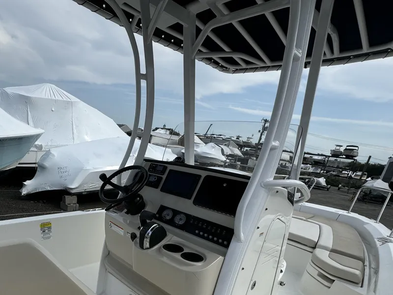 Slide: The Image of 2019 Boston Whaler 240 Dauntless boat interior with console and seating, parked outdoors. - 7