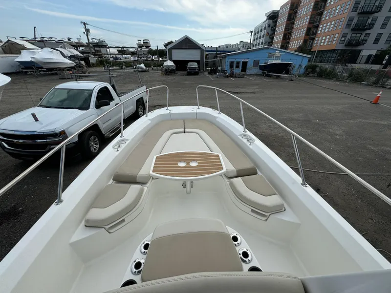 Slide: The Image of 2019 Boston Whaler 240 Dauntless boat with spacious seating and table, parked in a marina. - 9