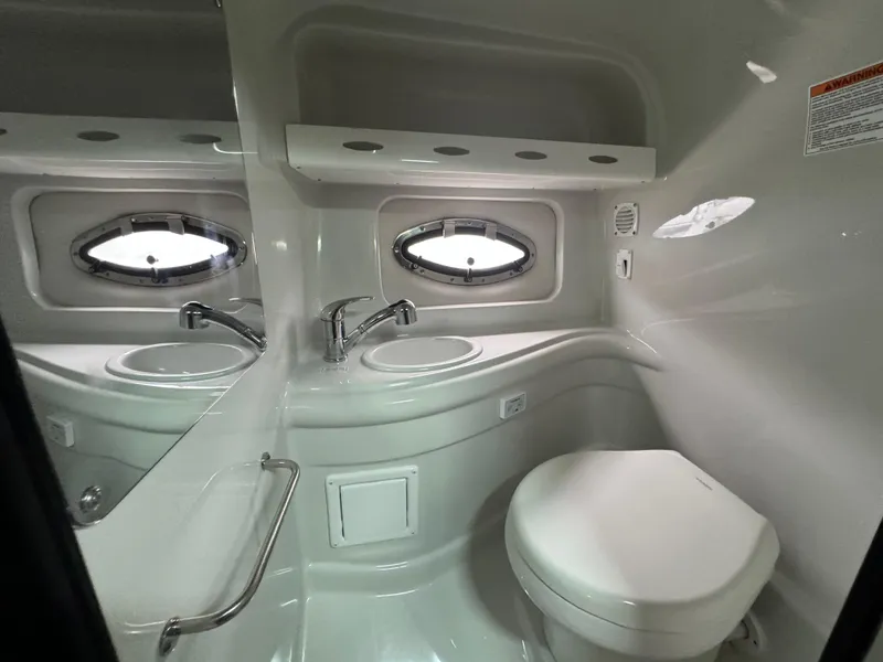 Slide: The Image of 2020 Crownline 286 SC boat bathroom with sink, toilet, and porthole window. - 17
