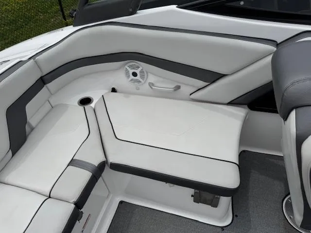 Slide: The Image of 2019 Yamaha AR240 boat interior with white and gray seating, cup holder, and speaker. - 19