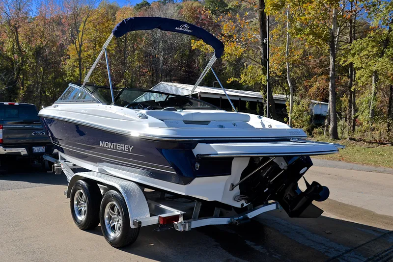 Slide: The Image of 2018 Monterey 204 FS boat on trailer, parked outdoors with trees in the background. - 12