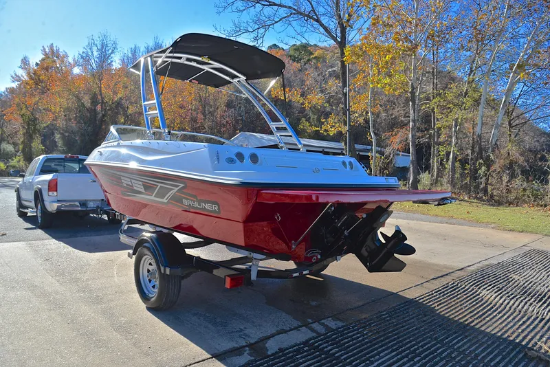 Slide: The Image of 2015 Bayliner 195 boat on trailer, parked near autumn trees. - 12