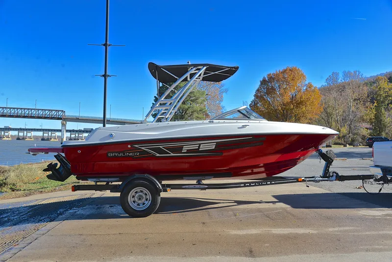 Slide: The Image of 2015 Bayliner 195 boat on trailer by riverside, under clear blue sky. - 15