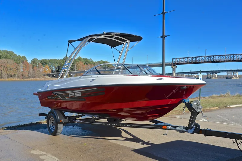 Slide: The Image of 2015 Bayliner 195 boat on trailer by riverside, under clear blue sky. - 16