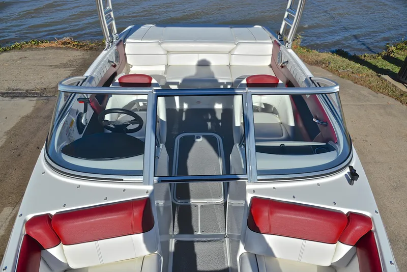 Slide: The Image of 2015 Bayliner 195 boat interior with red and white seating, docked by the water. - 20