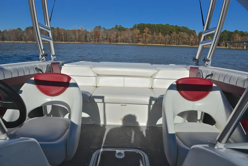 Slide: The Image of Interior of 2015 Bayliner 195 boat with white seating and red accents on a lake. - 22
