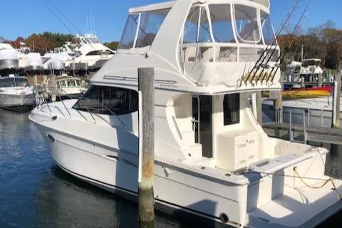 Slide: The Image of 2005 Silverton 34 Convertible yacht docked at marina, featuring fishing rods and spacious deck. - 1