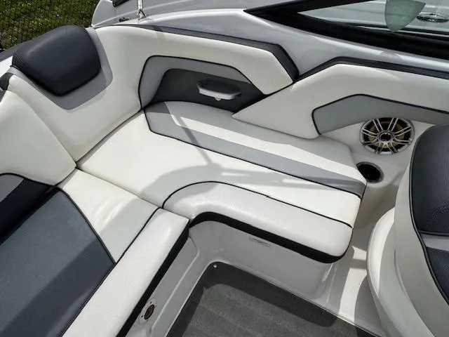 Slide: The Image of 2017 Yamaha Boats SX195 interior seating with white and black upholstery, featuring a speaker and cup holder. - 16