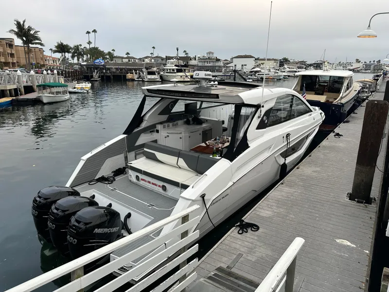 Slide: The Image of 2021 Cruisers Yachts 42 GLS OB docked in a marina, featuring triple Mercury outboard engines. - 24