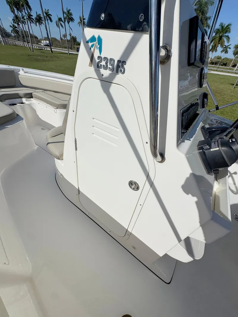Slide: The Image of 2023 Key West 239 FS boat console with seating and palm trees in the background. - 16