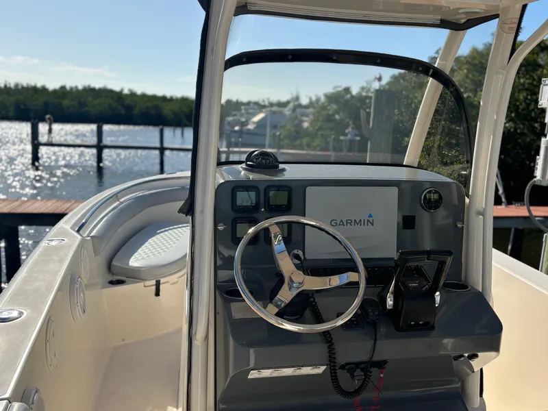 Slide: The Image of 2014 Pursuit C 260 Center Console boat with Garmin navigation, docked by a scenic waterfront. - 10