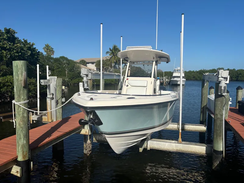 Slide: The Image of 2014 Pursuit C 260 Center Console boat docked on a lift in a scenic marina. - 3