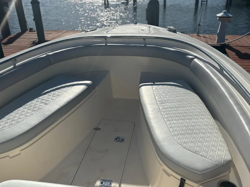 Slide: The Image of 2014 Pursuit C 260 Center Console boat interior with cushioned seating, dockside view. - 6