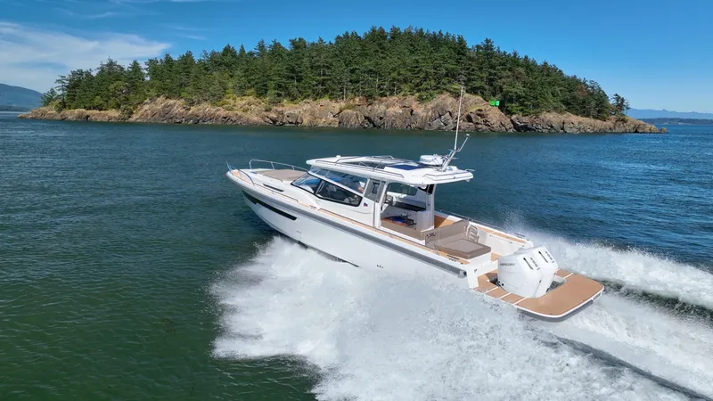 The Image of 2025 Nimbus W11 boat cruising on clear blue water near a forested island. - 0