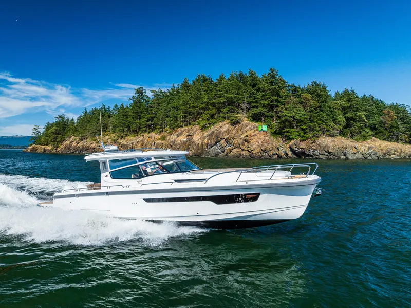 Slide: The Image of 2025 Nimbus W11 yacht cruising on clear blue waters near a lush island. - 2
