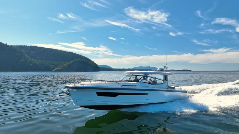 Slide: The Image of 2025 Nimbus W11 boat cruising on scenic lake with forested island backdrop. - 4
