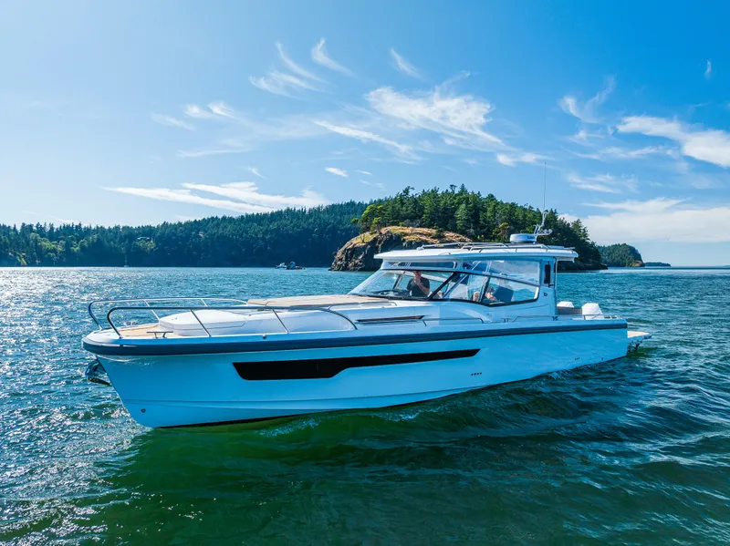 Slide: The Image of 2025 Nimbus W11 boat cruising near a forested island on a sunny day. - 5