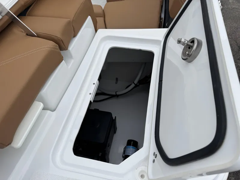 Slide: The Image of 2025 Four Winns H2 OB boat storage compartment with open hatch and tan seating. - 16