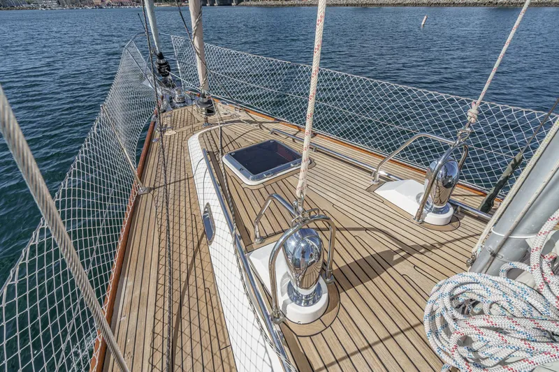 Slide: The Image of 2012 Hylas 46 sailboat deck with polished fittings and safety netting on calm water. - 6