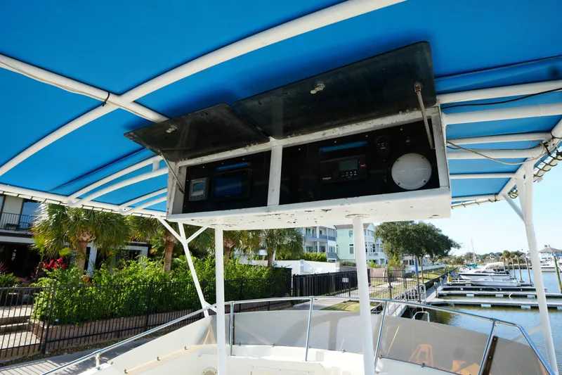 Slide: The Image of 1987 Hatteras 36 Convertible boat with blue canopy and control panel, docked at marina. - 11