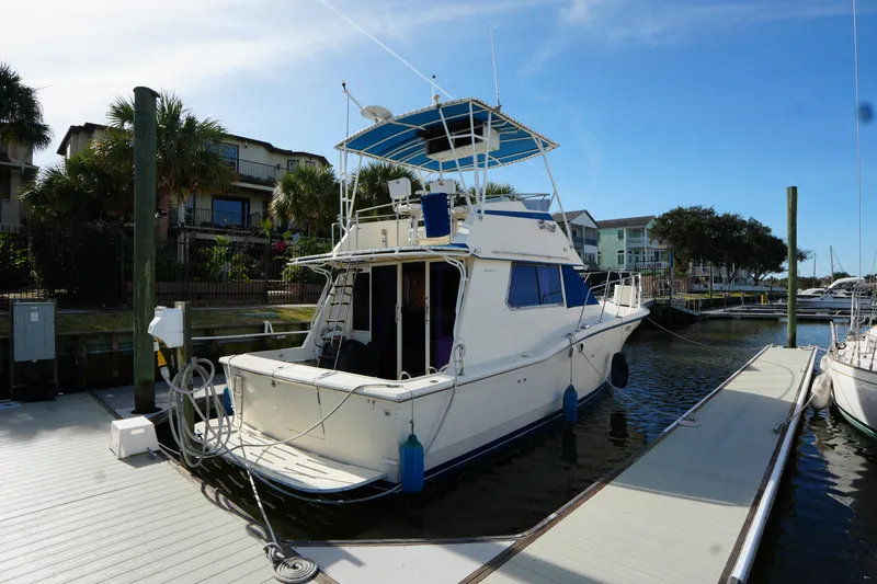 Slide: The Image of 1987 Hatteras 36 Convertible yacht docked at marina under clear blue sky. - 12