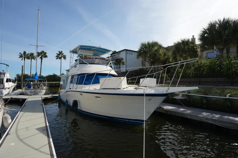Slide: The Image of 1987 Hatteras 36 Convertible yacht docked, surrounded by palm trees and calm water. - 13