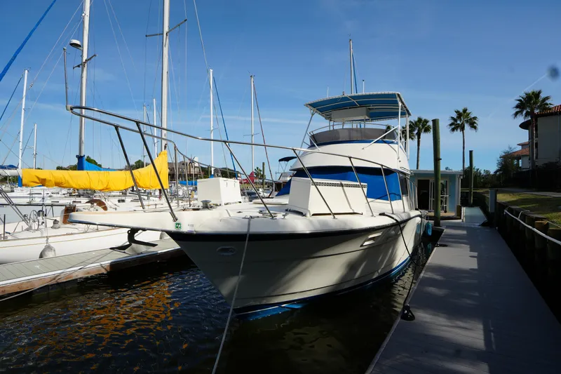 Slide: The Image of 1987 Hatteras 36 Convertible yacht docked at marina with sailboats and palm trees. - 15