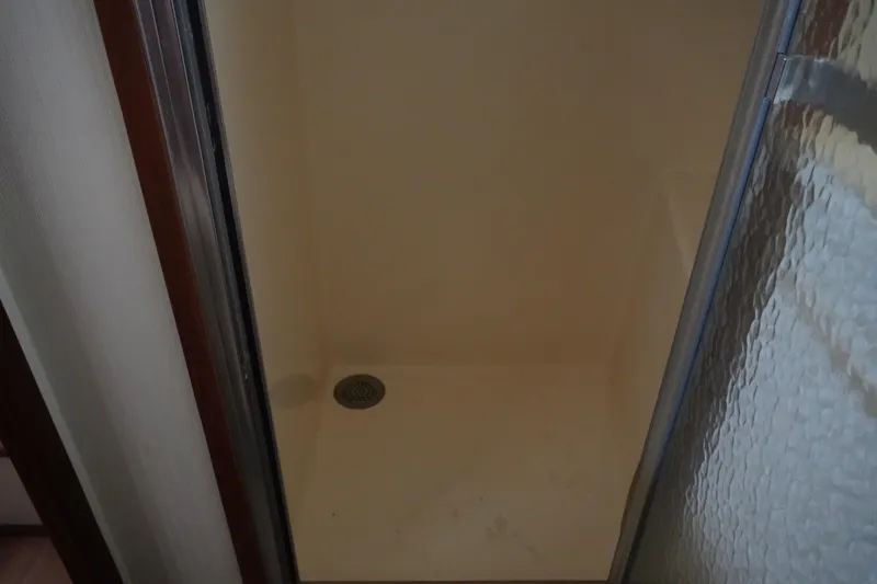 Slide: The Image of Shower area inside 1987 Hatteras 36 Convertible boat, featuring a glass door and drain. - 25