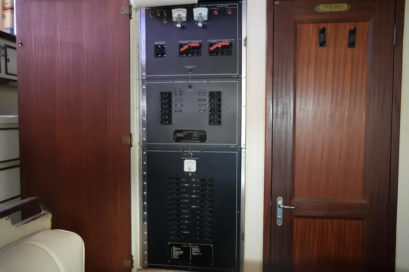 Slide: The Image of Electrical panel inside 1987 Hatteras 36 Convertible yacht, next to wooden door labeled "Head". - 29