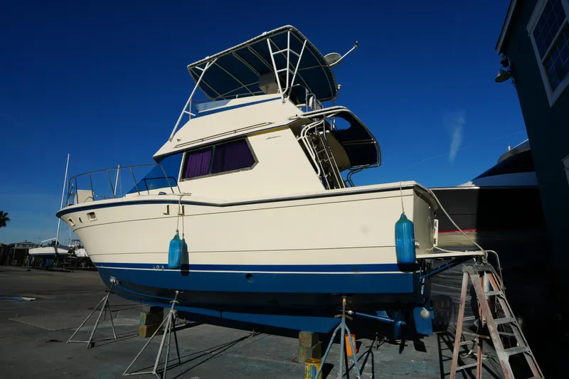 Slide: The Image of 1987 Hatteras 36 boat on stands, blue and white hull, clear sky background. - 40