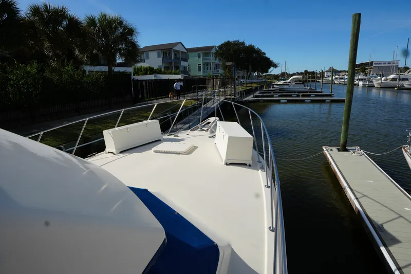 Slide: The Image of 1987 Hatteras 36 Convertible yacht docked at marina, surrounded by palm trees and waterfront homes. - 5