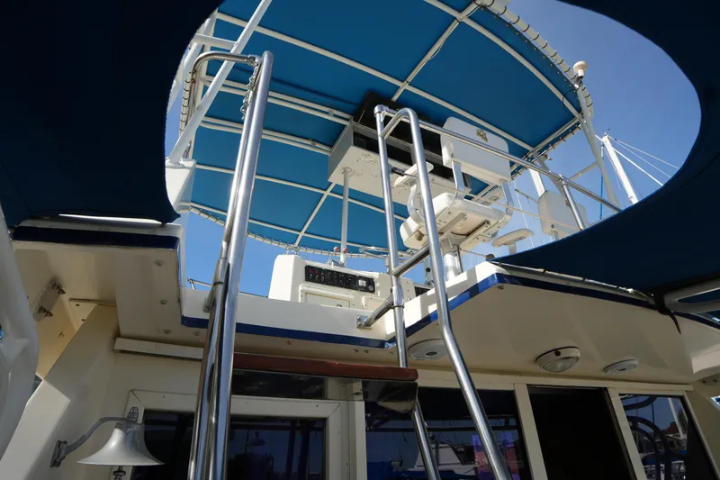 Slide: The Image of 1987 Hatteras 36 Convertible yacht with blue canopy and ladder to upper deck. - 8