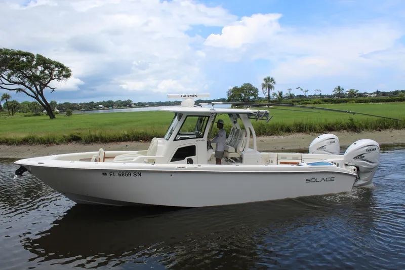 Slide: The Image of 2020 Solace 345 CC boat cruising on a calm river with scenic greenery. - 0