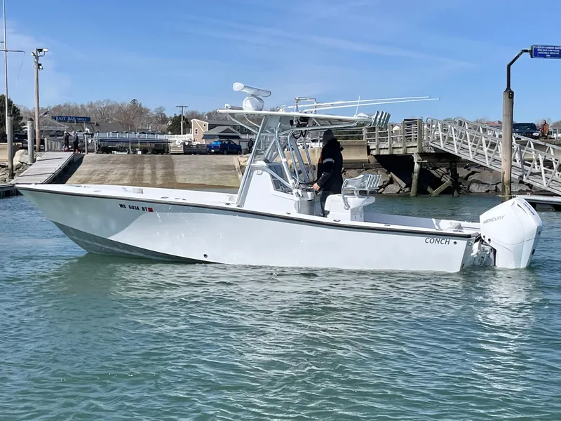 Slide: The Image of 2022 Conch 27 CC boat on water near dock, clear sky background. - 1