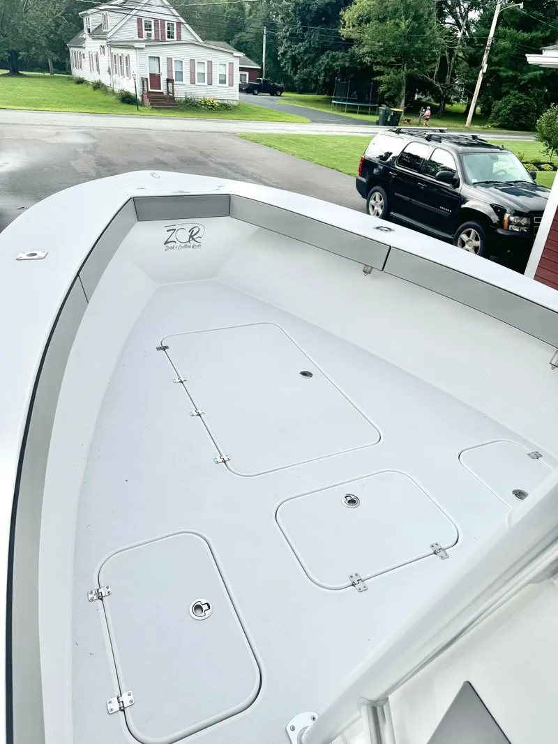 Slide: The Image of 2022 Conch 27 CC boat deck with storage compartments, parked near a house and SUV. - 3