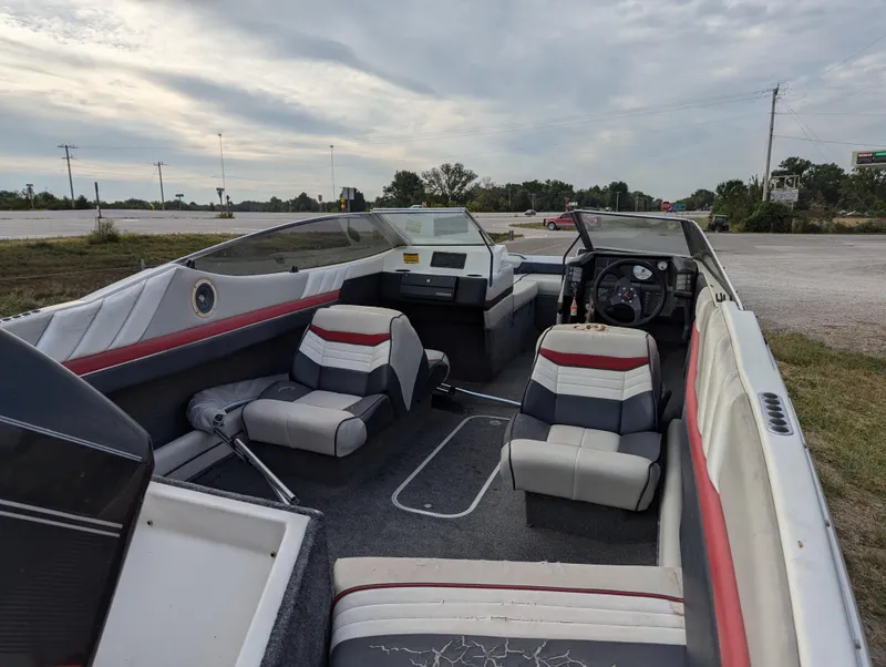 Slide: The Image of 1990 Bayliner 180 Capri boat interior with red and gray seating, parked outdoors. - 13