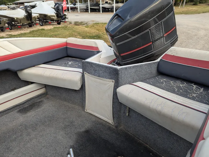 Slide: The Image of 1990 Bayliner 180 Capri boat interior with seating and motor, parked outdoors. - 15