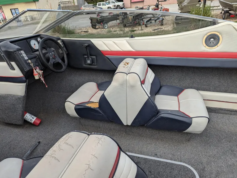 Slide: The Image of 1990 Bayliner 180 Capri boat interior with gray and red seating, steering wheel, and dashboard. - 16