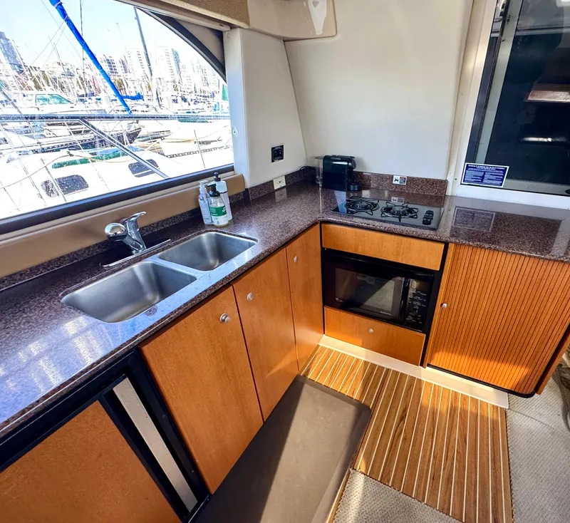 Slide: The Image of 2002 Bayliner 3488 Command Bridge kitchen with sink, stove, and wood cabinetry. - 26
