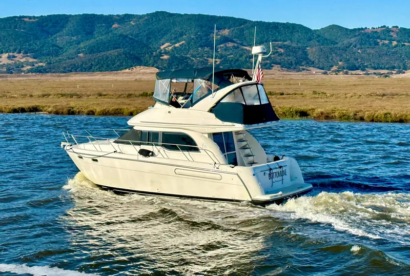 Slide: The Image of 2002 Bayliner 3488 Command Bridge cruising on a scenic river with hills in the background. - 4