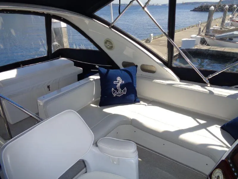 Slide: The Image of 2002 Bayliner 3488 Command Bridge interior with nautical-themed decor, docked by the water. - 8