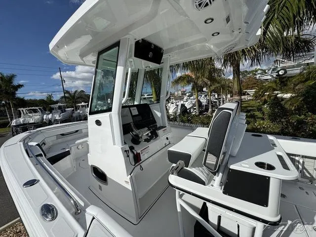 Slide: The Image of 2025 Blackfin 252CC boat interior with modern console and seating, surrounded by palm trees. - 19